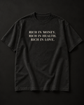 RICH IN MONEY. RICH IN HEALTH. RICH IN LOVE. heavyweight tee in washed black with a three-line stacked serif front print.
