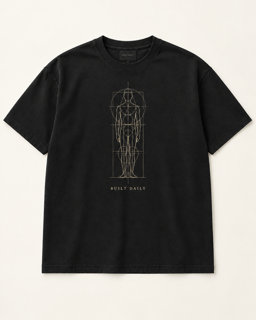 The Blueprint heavyweight tee in near-black with a muted gold blueprint linework figure and BUILT DAILY caption.